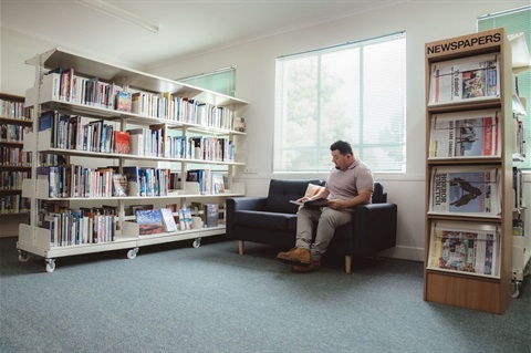 Photo of man on couch reading in Heywood Library