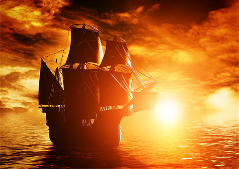 A picture of a pirate ship sailing into the sunset